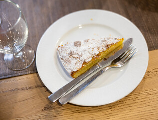 Traditional Spanish cake with almonds Tarta de Santiago on white plate. Delicious dessert with nuts according to a traditional Spanish recipe