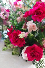 Close-up of floral arrangement with red, pink, and white roses, greenery, and small pink blossoms. Studio flower photography. Wedding floral decoration and romantic botanical concept. Design for greet