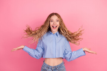 Excited young woman with charming smile in casual outfit making cheerful gestures against pink...
