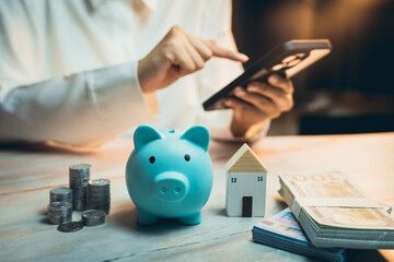 Home buying concept. Person Using Smartphone for Financial Management with Piggy Bank, House Model,...