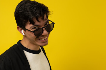 Close up of a young freckled man in profile with a mustache smiling with glasses and wireless...