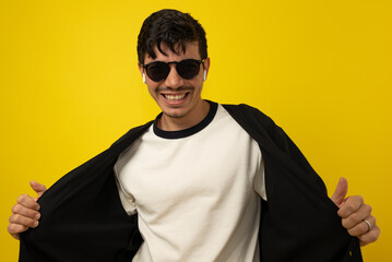 Young freckled man with a mustache smiling with glasses and wireless headphones on a yellow...