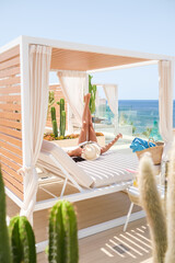 Faceless woman chilling on canopy bed on sunny day
