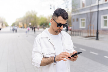 Businessman in white clothes using smartphone in city