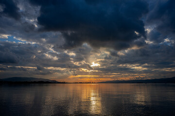 Dramatic Cloudy Sunset Over the Sea in Başiskele, Kocaeli, Türkiye with Golden Reflections and Industrial Silhouettes
