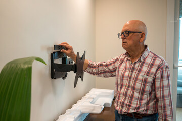 Elderly man installing a wall-mounted TV bracket