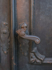 Part of a  front door, made of wood, black in color, metal handle, interesting shape