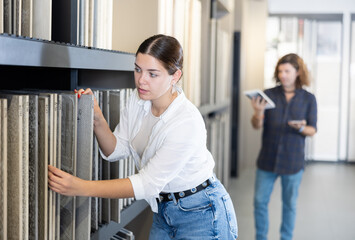 Focused woman choosing wall tiling materials in hardware shop