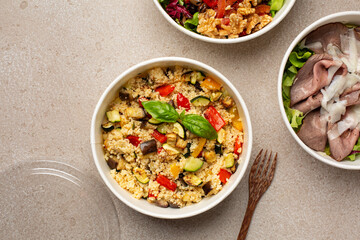 Round recyclable lunchboxes with healthy food, prep meal concept.  Couscous with roasted vegetables,  roast Beef and lettuce, vegetarian salad with walnuts. Top view.