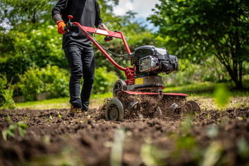 Farmer plows the land with a cultivator, preparing it for planting vegetables, on a sunny day...