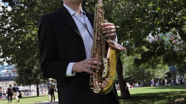 Young saxophonist plays beautiful classical music in the par