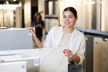 female buyer inspects decorative tiles for redecorate apartment of new flat. Interior decor,...