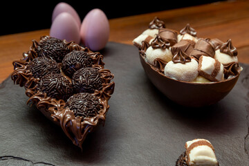 Chocolate easter eggs on top of black stone with wooden background