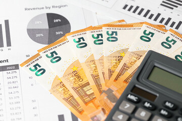 Fifty euro banknotes with calculator. Financial planning and eurozone budget concept. Business report and statistics. Money saving strategy. Economic analysis with currency and data charts.