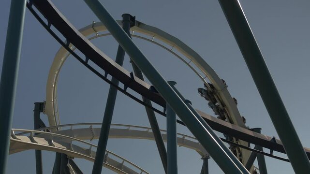 Experience the excitement of an unforgettable roller coaster ride at amusement park. Witness the thrilling drops and turns that leave riders screaming with joy against a clear sky.