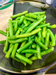 Fresh green beans arranged neatly in a glass bowl on a kitchen counter during meal preparation