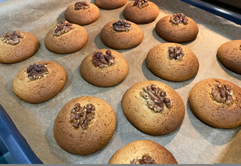 Freshly baked cookies with walnuts arranged on a tray ready to cool in the kitchen