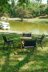 Obraz premium Camping table and Camp chair set in garden on a sunny day near river,outdoor seating for restaurant or cafe.