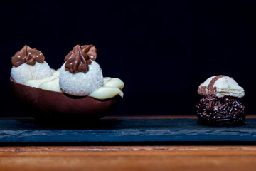 Chocolate easter egg and chocolate truffle on top of black stone with wooden background