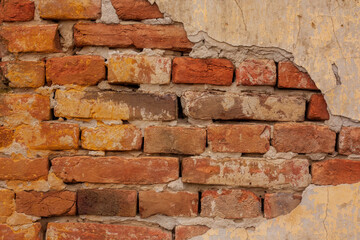 Aged red brick wall with peeling plaster
