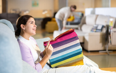 Woman choosing material for sofa in furniture showroom