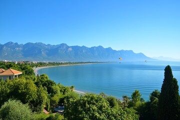 Obraz premium Overhead view of Antalya, featuring its Mediterranean beach and coastline, with a paraglider, Antalya, Turkey