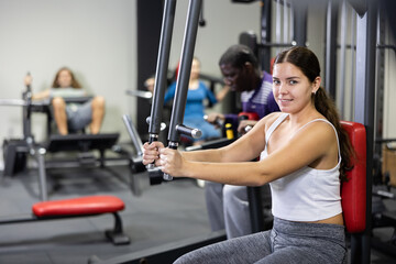 Fototapeta premium Caucasian woman using chest fly machine for training in gym