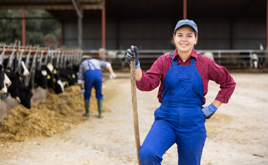 Portrait of smiling European female farmer in uniform with rake during work on dairy farm © JackF