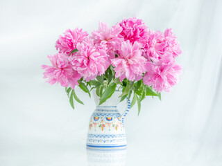 view to bouquet of pink peonies in vase on table in high key