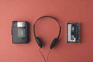 Retro cassette player, headphones, and tape arranged on red background bring authentic 90s...
