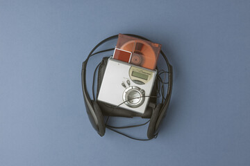 Compact minidisc player with wired headphones and a single orange disc on blue background brings...