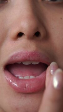 Close up footage of attractive young Asian getting ready while applying lip balm on her lips.