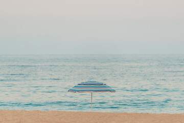 Lonely sun umbrella parasol at sandy beach on overcast summer day