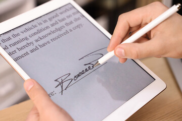 Electronic signature. Man using stylus and tablet at table, closeup