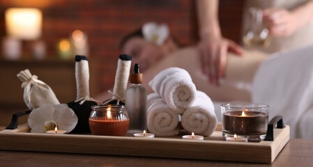 Woman receiving back massage with oil indoors, focus on different spa supplies