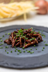 Shimeji mushroom served with chives on black stone plate. Typical oriental meal. Detail of food dish, closeup, selective focus.