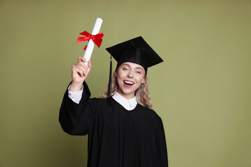 Happy student with diploma after graduation on green background