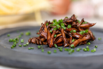 Shimeji mushroom served with chives on black stone plate. Typical oriental meal. Detail of food dish, closeup, selective focus.