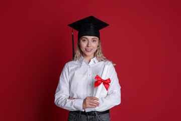 Happy student with diploma after graduation on red background