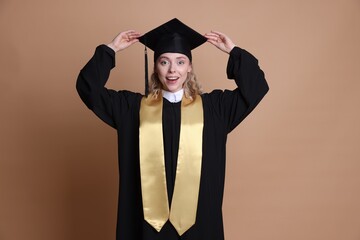 Happy student after graduation on beige background