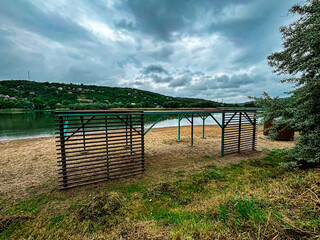 A quiet beach scene on a cloudy day with a simple wooden sunshade structure standing on the sand....