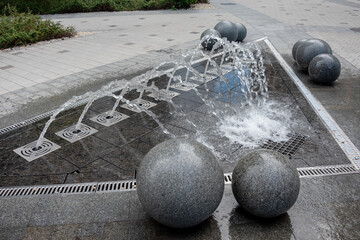 Outdoor decorative fountain with round marble sculptures and flowing water streams.