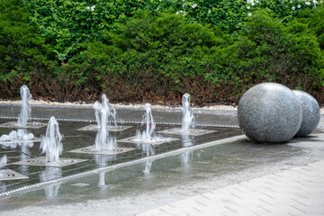 Outdoor decorative fountain with round marble sculptures and flowing water streams.