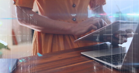 Image of data processing against mid section of woman using laptop and digital tablet