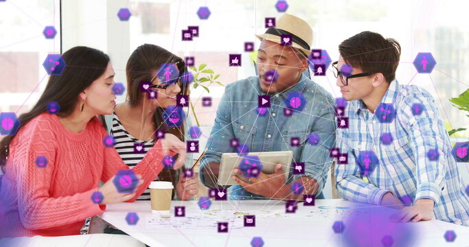 Globe of digital icons over group of diverse office colleagues using digital tablet at office