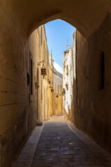 Fototapeta premium Narrow alleyway in the old city of Mdina with traditional lanterns, ragged limestone houses and tranquil atmosphere, Maltese Islands.