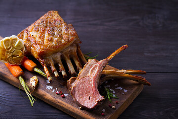Roasted rack of lamb. Lamb chops on serving board and black wooden background