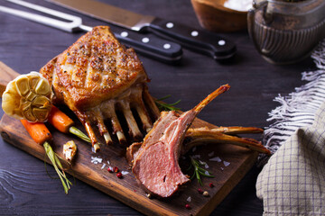 Roasted rack of lamb. Lamb chops on serving board and black wooden background