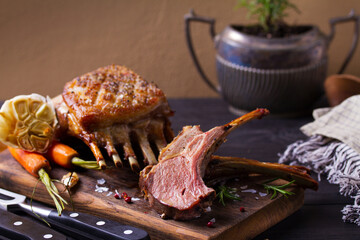 Roasted rack of lamb. Lamb chops on serving board and black wooden background