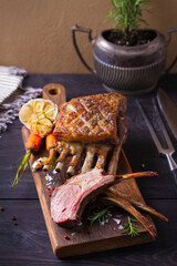 Roasted rack of lamb. Lamb chops on serving board and black wooden background